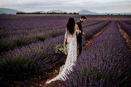 The bride and groom in a lavender field, the bride wearing a modern bouquet, boho style wedding, floral design Lilas Wood florist wedding in Provence alpes côte d'azur - Photography Chris and Ruth.